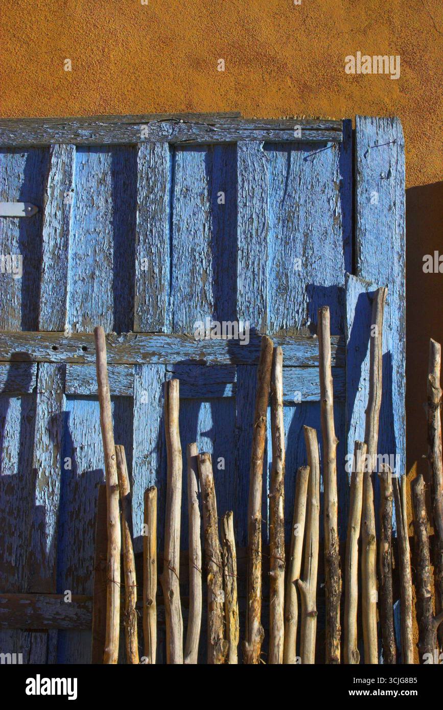 Typical patterns of the american southwest, with adobe clay wall, blue antique door and old wood branch fence Stock Photo