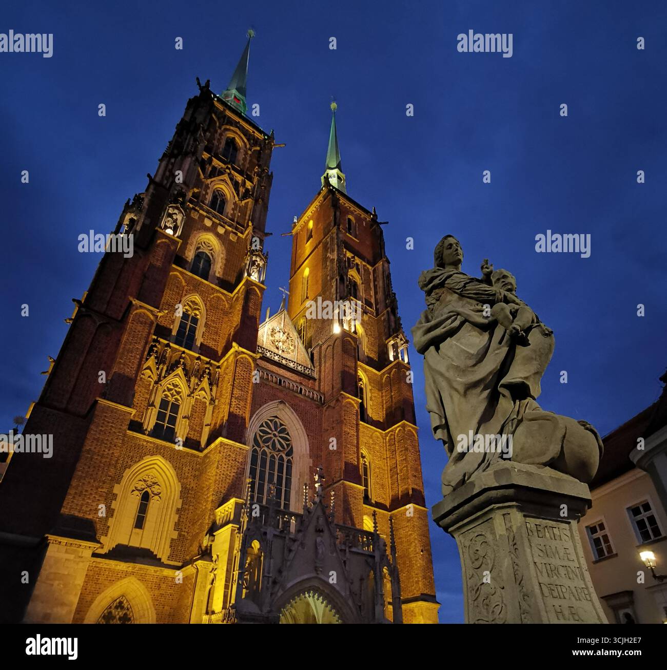 St John the Baptist Cathedral twin spires lit at night, Wrocław. Foreground: Baroque statue, Ostrów Tumski, Cathedral Island. - Smartphone Captured Stock Image