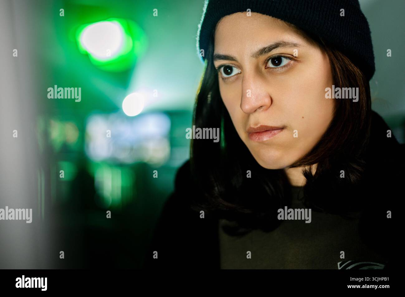 Female young hacker working on computer in dark room programming code Stock Photo