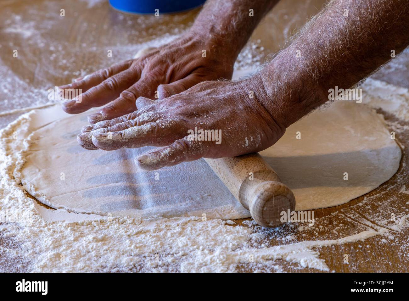 A pizza base being rolled out  with a rolling pin, with selective focus Stock Photo