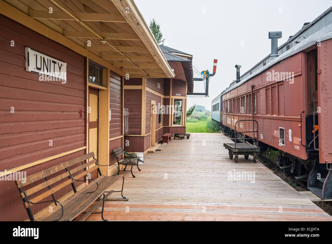 Train station with a red building and a sign that says Unity. There are ...