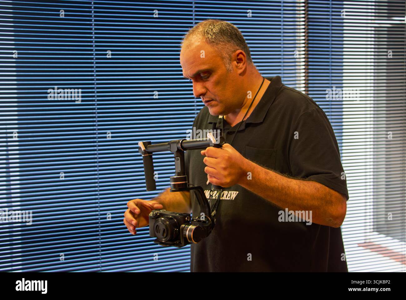 cameraman operating a handheld motorized gimbal stabilizer to keep the camera steady in motion, indoors at a corporate shoot Stock Photo