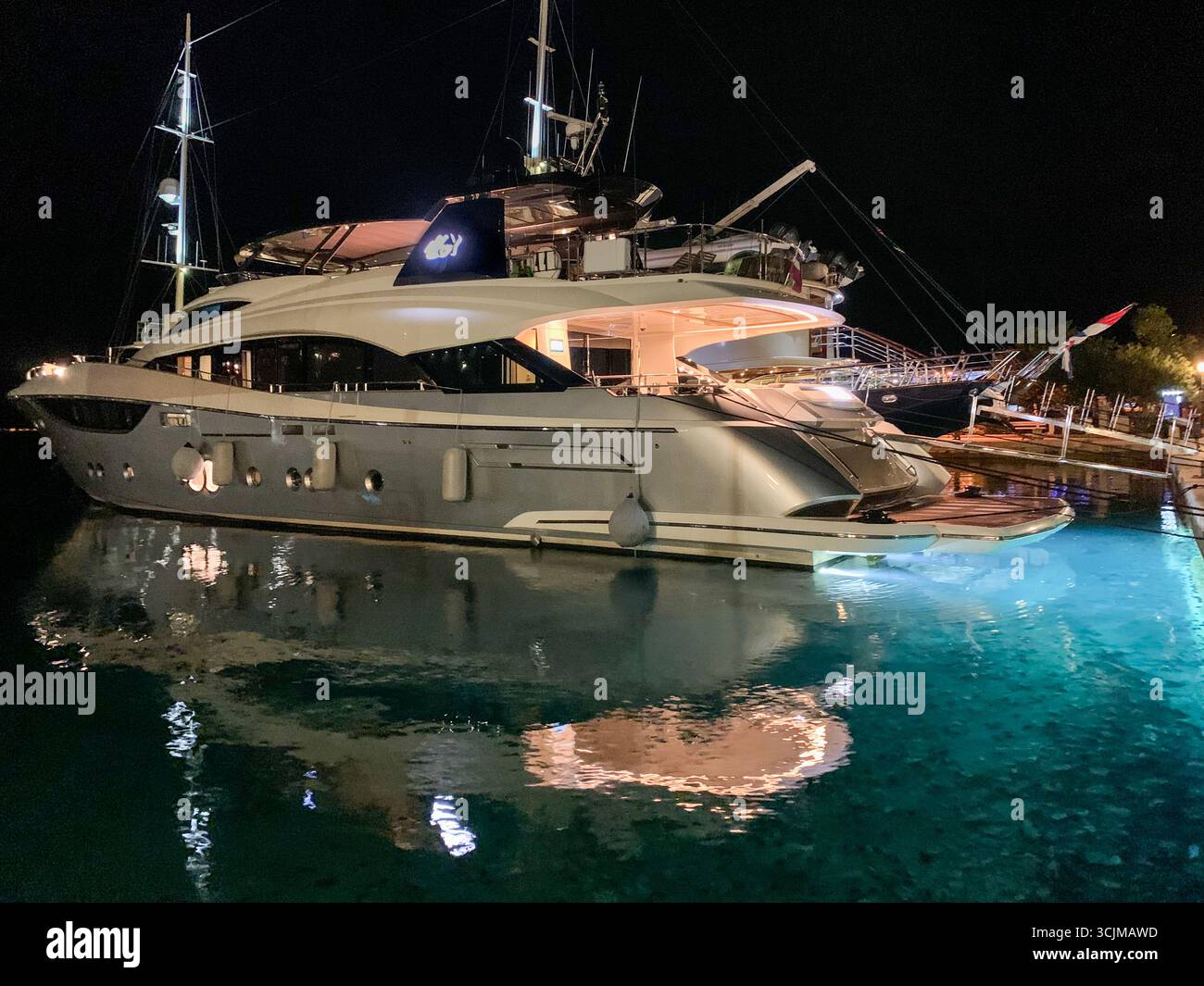 Korcula, Croatia: Luxury motor yacht, stunning submarine underwater lights illuminating the blue turquoise waters, under water boat illumination - Smartphone Captured Stock Image