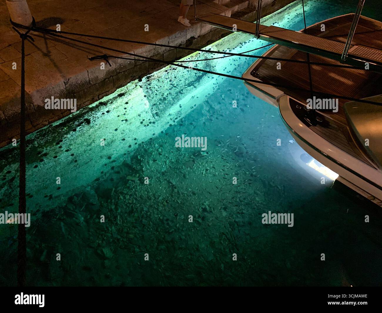 Korcula, Croatia: Luxury motor yacht, stunning submarine underwater lights illuminating the blue turquoise waters, under water boat illumination - Smartphone Captured Stock Image