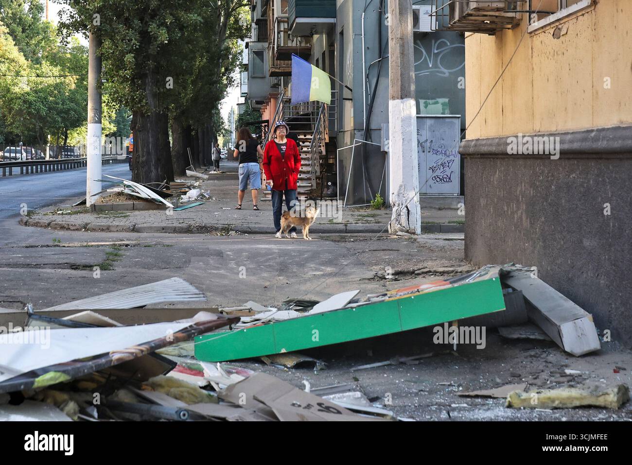 A woman walking a dog looks up at an apartment building damaged by a Russian drone attack, Odesa, Ukraine, on September 7, 2025. (Photo by Nina Liashonok/Ukrinform) Stock Photo