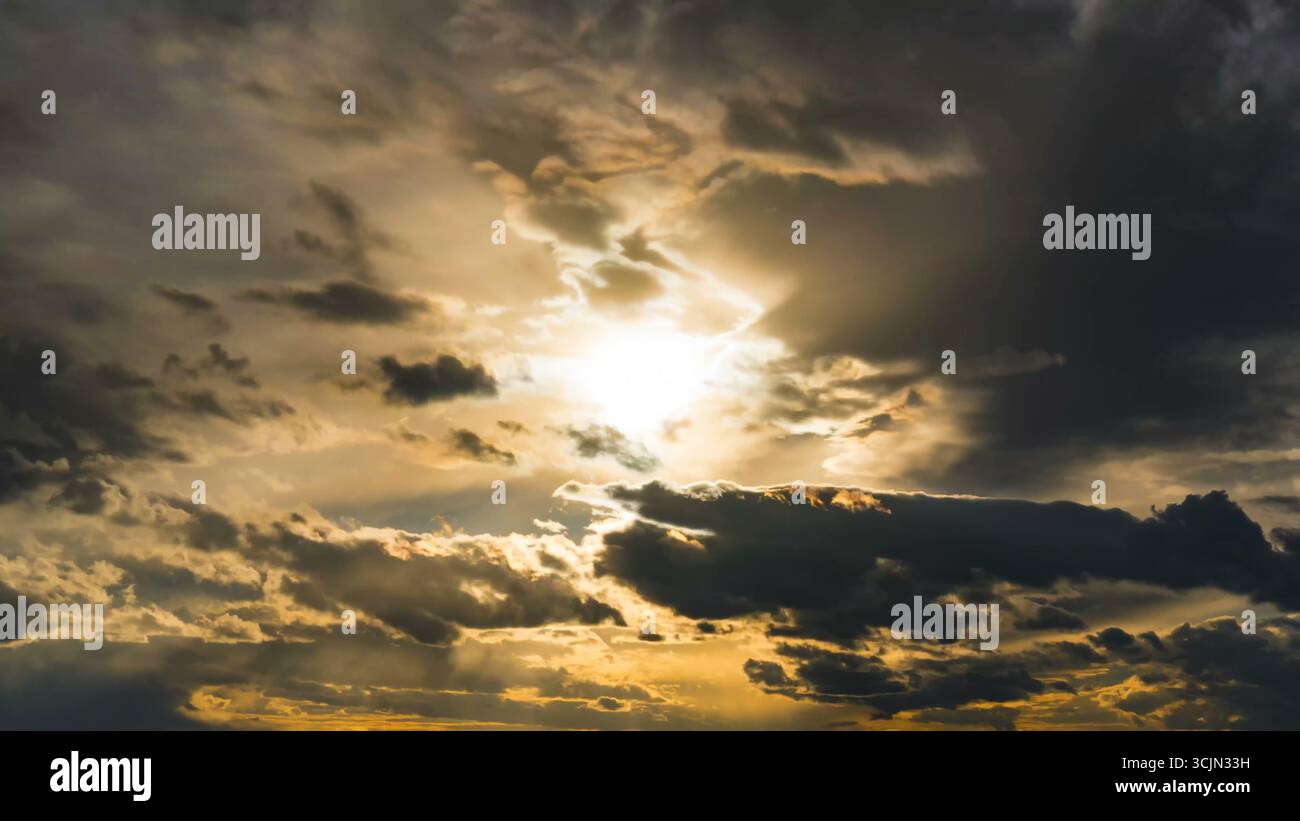 Sunset through dramatic cloudy sky with sunbeams Stock Photo