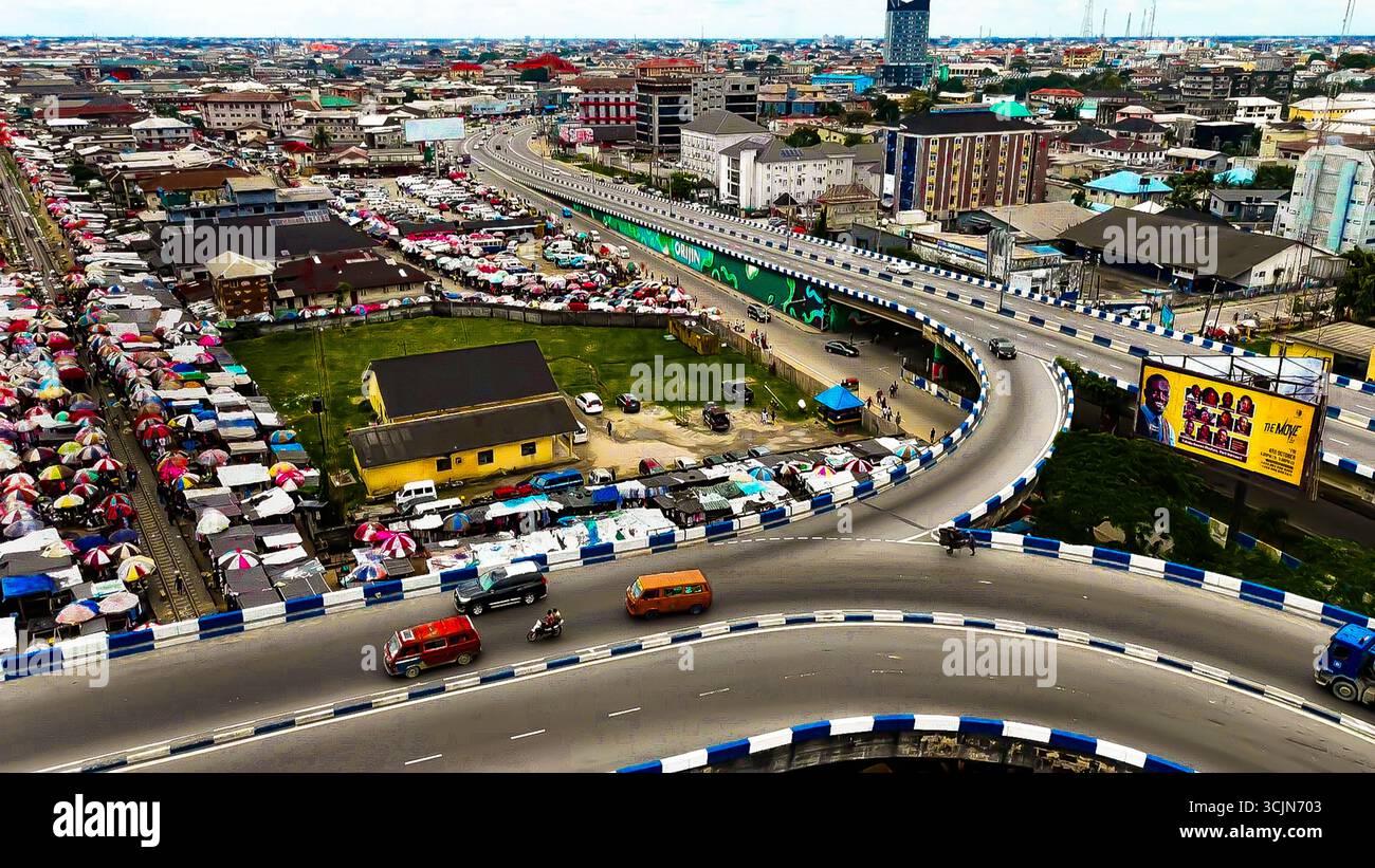 Aerial view of a bustling Lagos cityscape with a vibrant marketplace sprawling beneath an elevated highway, Isaac Boro Park, Port Harcourt, Rivers State, Nigeria. Stock Photo