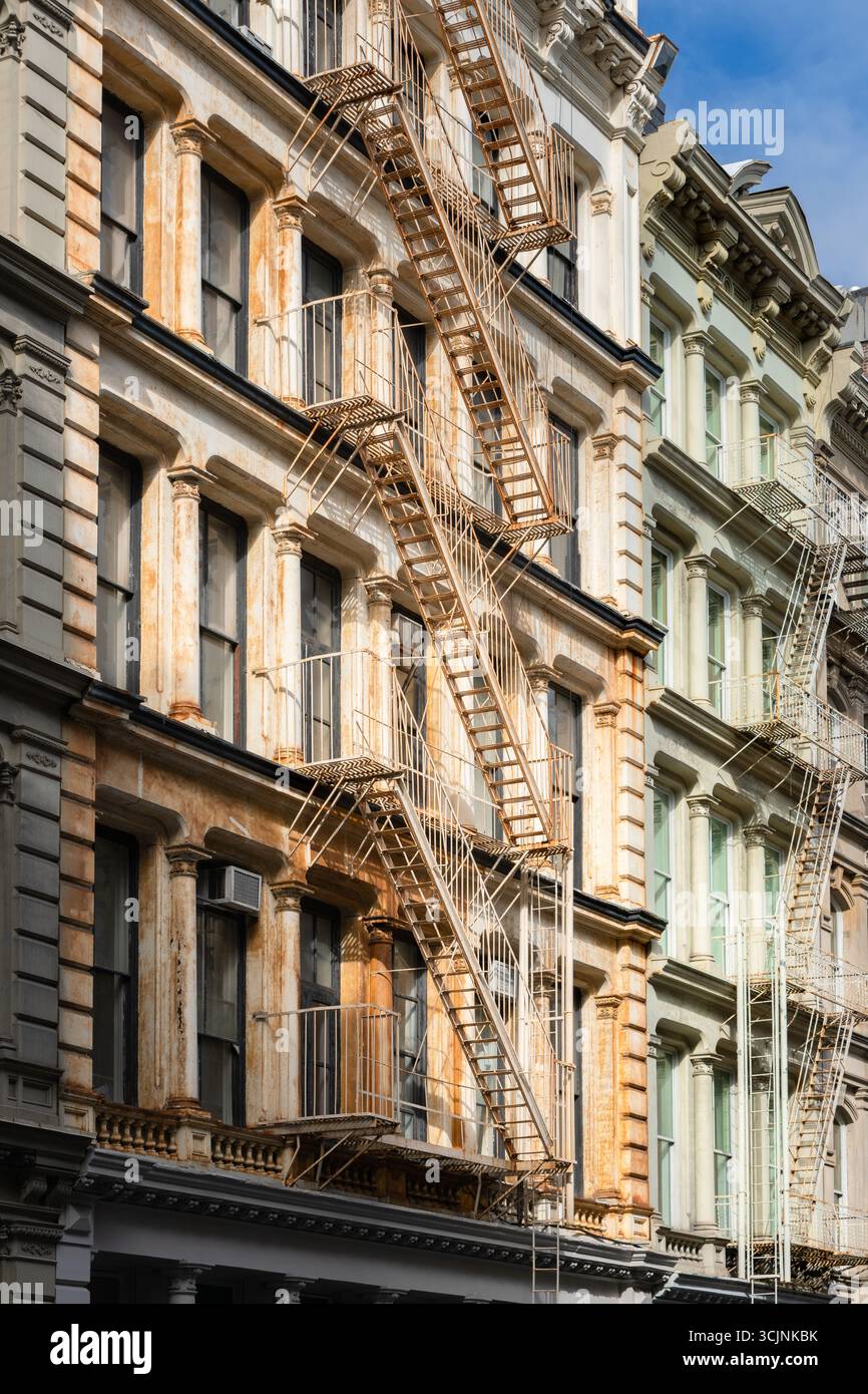 Weathered cast-iron facade with rust on columns and fire escapes. Classic SoHo Cast Iron Historic District architecture in Manhattan, New York City Stock Photo