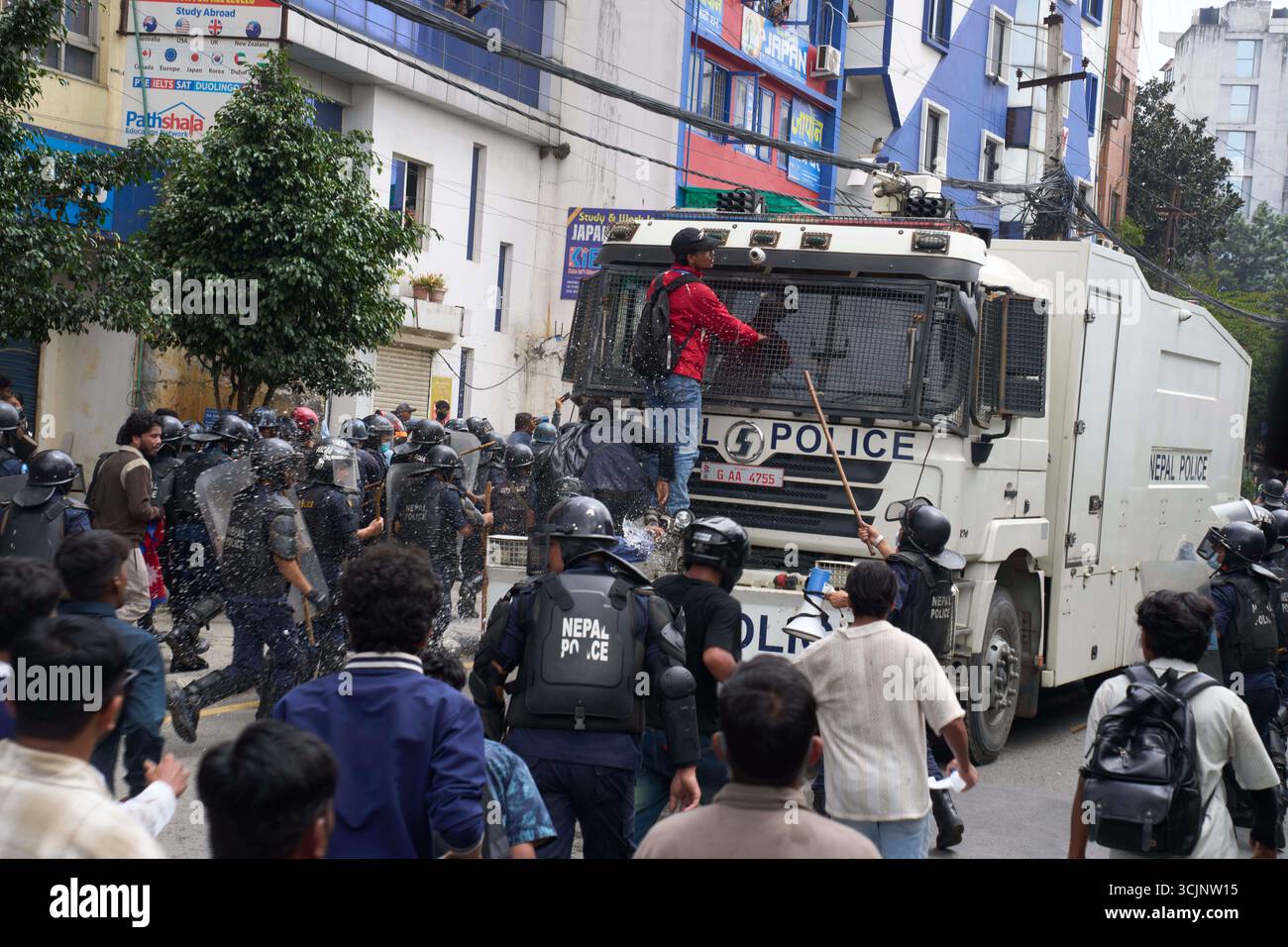 A protester stands on a police vehicle during clashes with riot police ...
