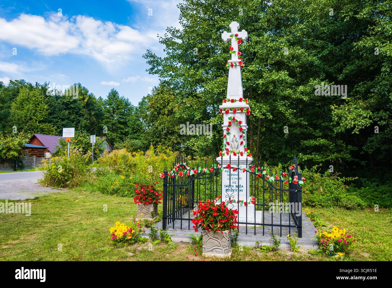 Small roadside catholic chapel decorated with flowers on tree in forest, Roztocze region, Poland Stock Photo
