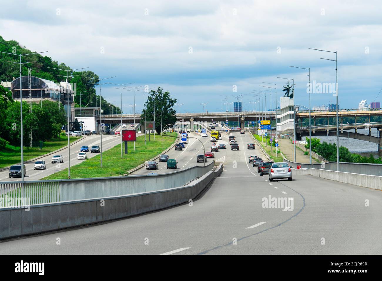 Kyiv, Ukraine - 06.29.2025: Wide-angle view of a busy multilane highway with cars and bridges on a bright, cloudy day Stock Photo