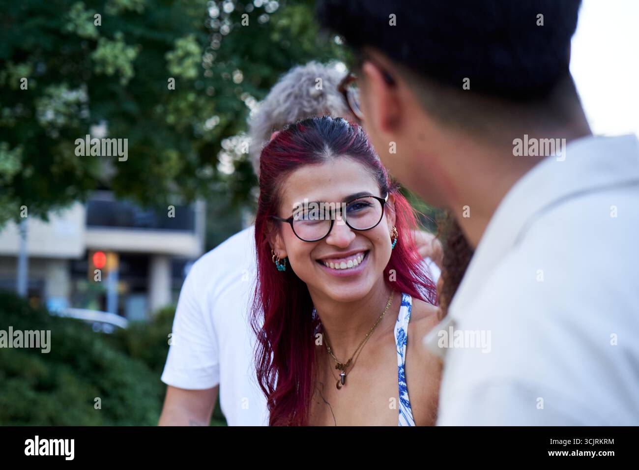 Young woman smiling and talking with friends outdoors in urban setting. Stock Photo