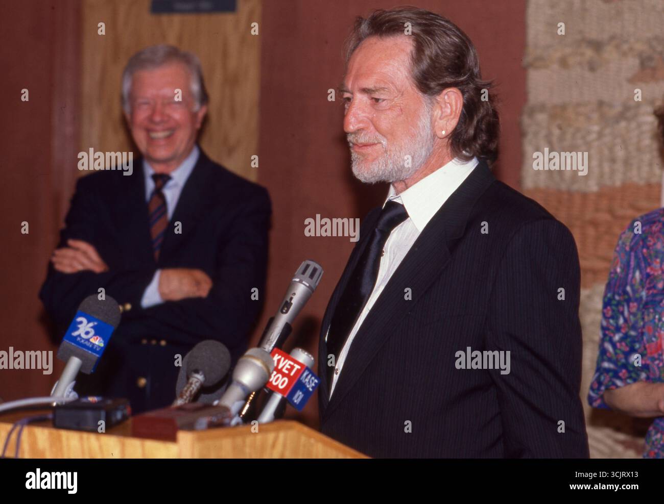 Former U.S. President JIMMY CARTER, l, watches as musician  WILLIE NELSON  makes a speech before executives at a Habitat for Humanity fund-raiser in Austin on August 2, 1989. Stock Photo