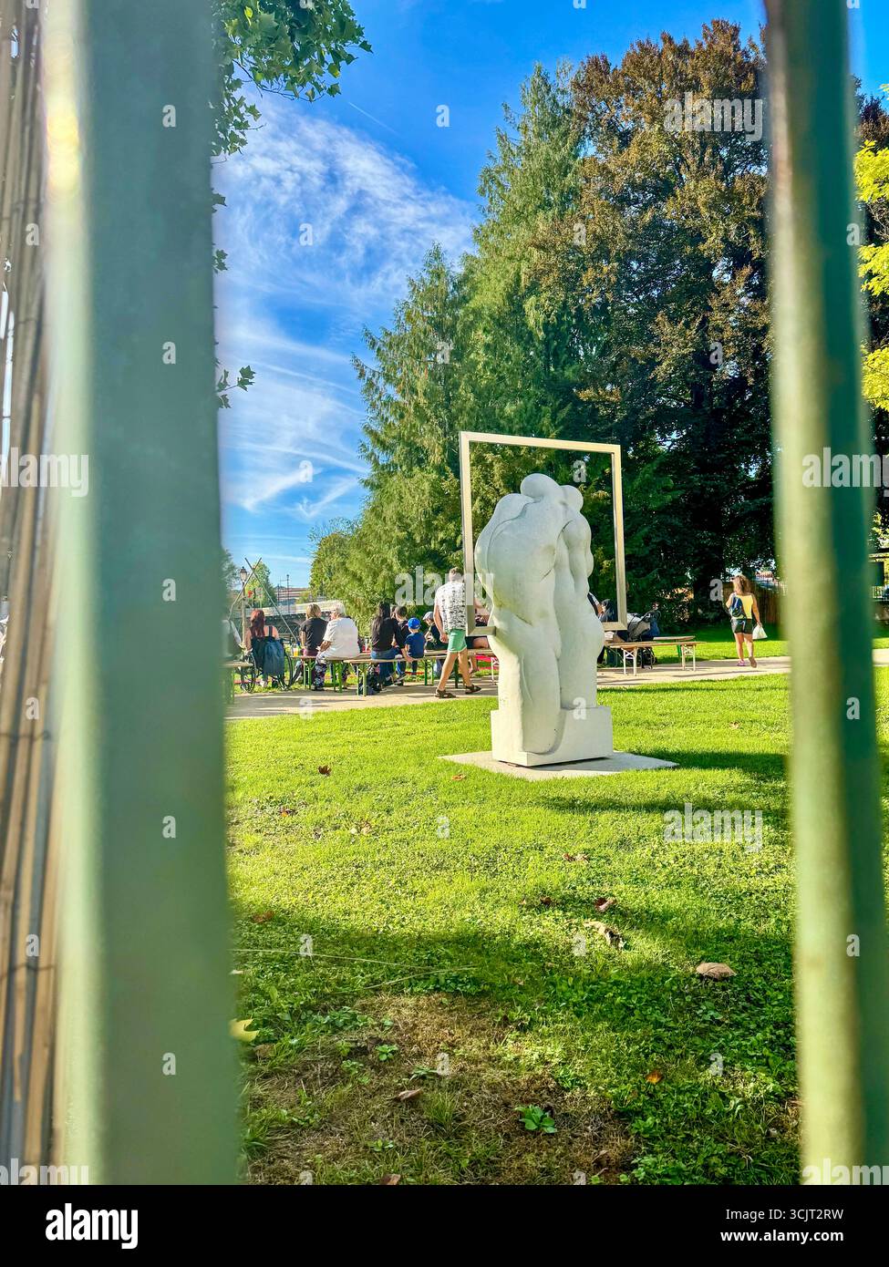 white abstract sculpture in a public park, during the 'campagne a la ville' event in Audincourt, with people gathered in the background on a sunny day - Smartphone Captured Stock Image