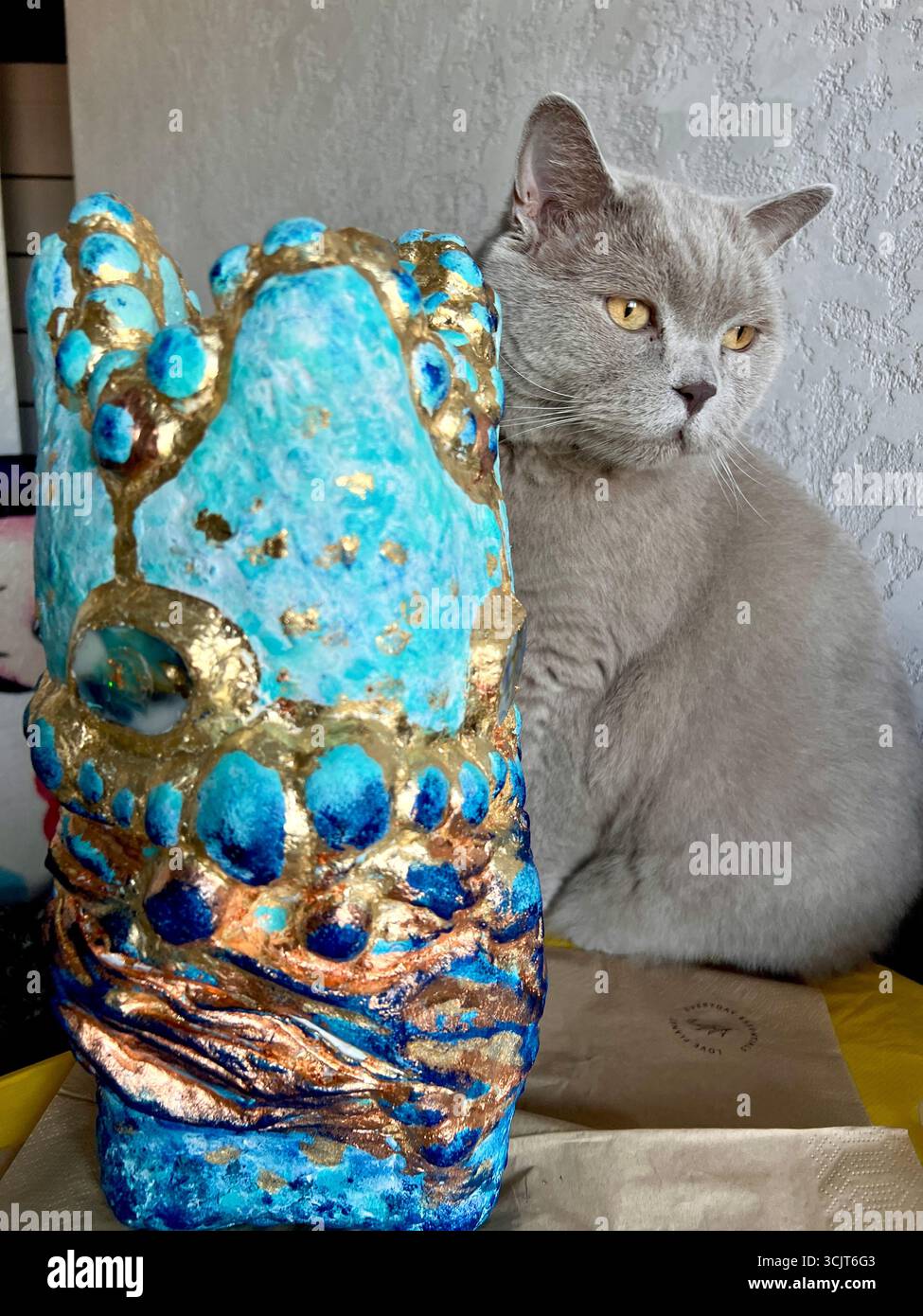 A beautiful gray British cat sits near a blue art vase. - Smartphone Captured Stock Image