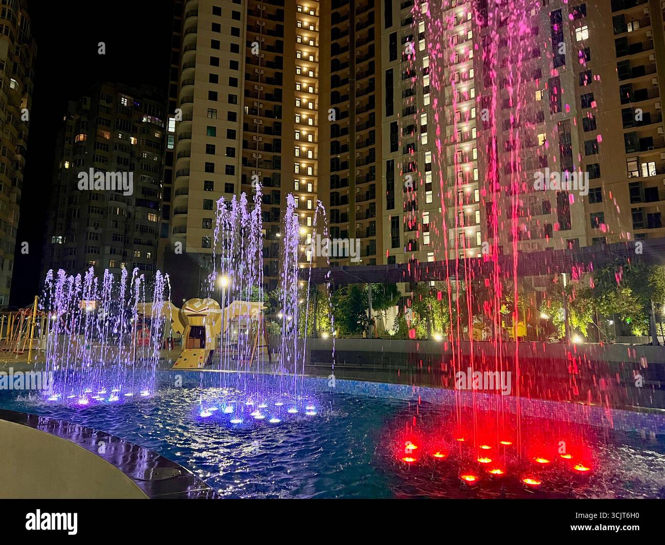 singing fountain with purple and yellow colored lighting in the middle of the city area - Smartphone Captured Stock Image