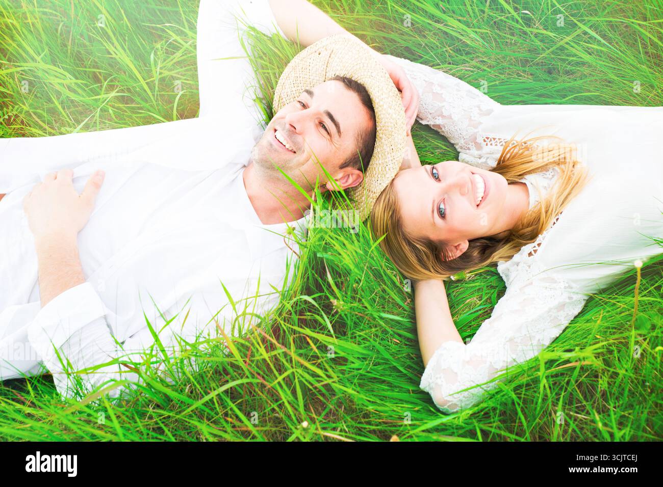 young couple lying head to head happily in a meadow Stock Photo