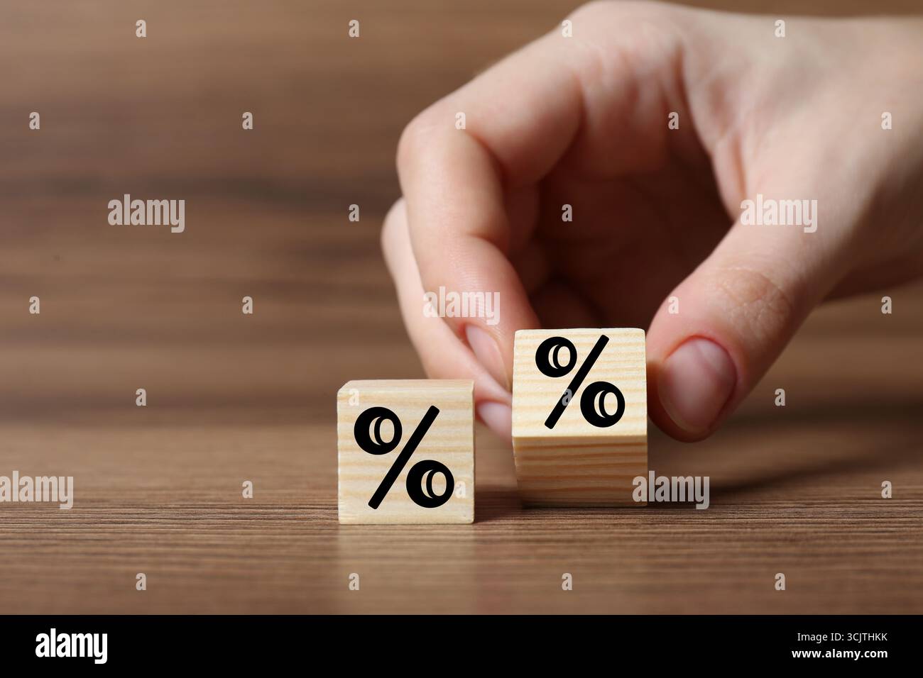 Man holding wooden cube with percent sign at table, closeup Stock Photo