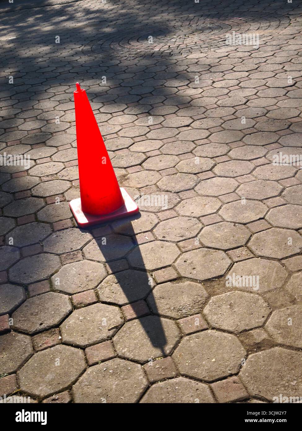 An eye-catching cone sign stands on the concrete block sidewalk. Stock Photo