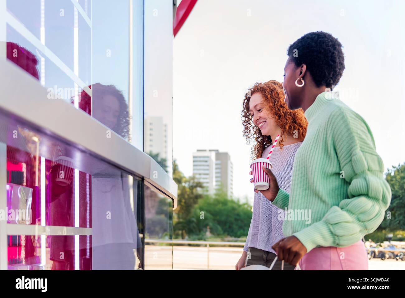 two happy young women standing outside a store Stock Photo - Alamy
