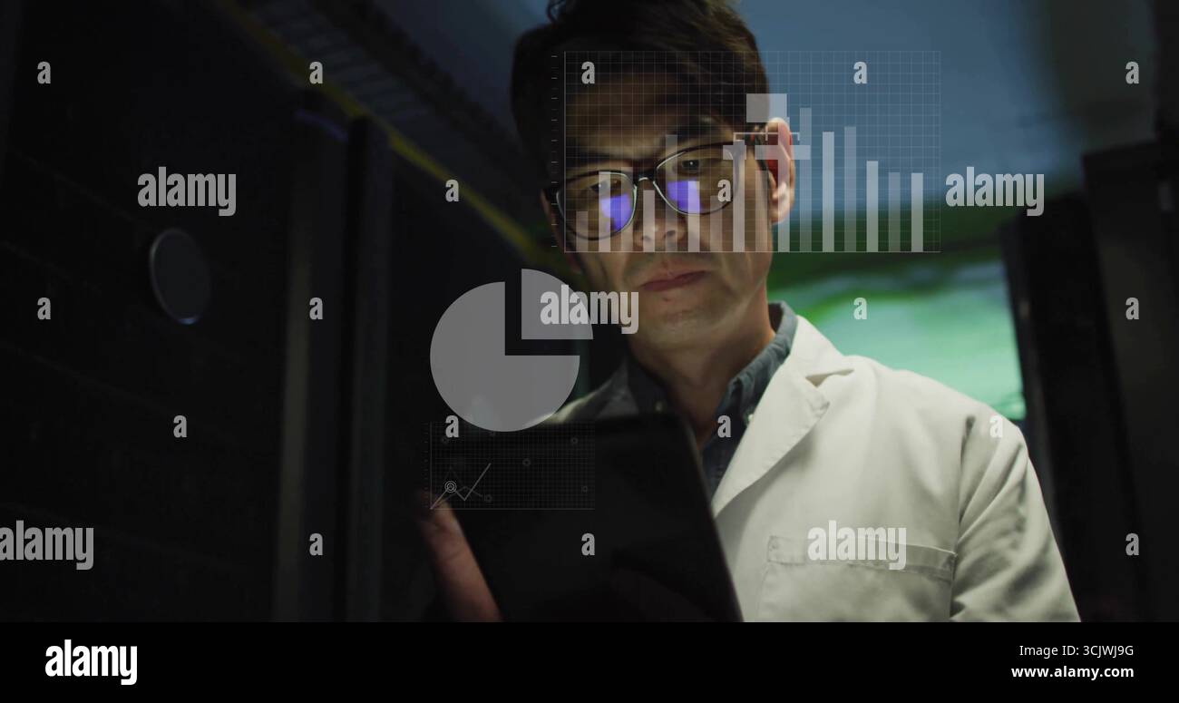 Analyzing tablet data, Korean man in lab coat standing between server racks, showing digital charts Stock Photo