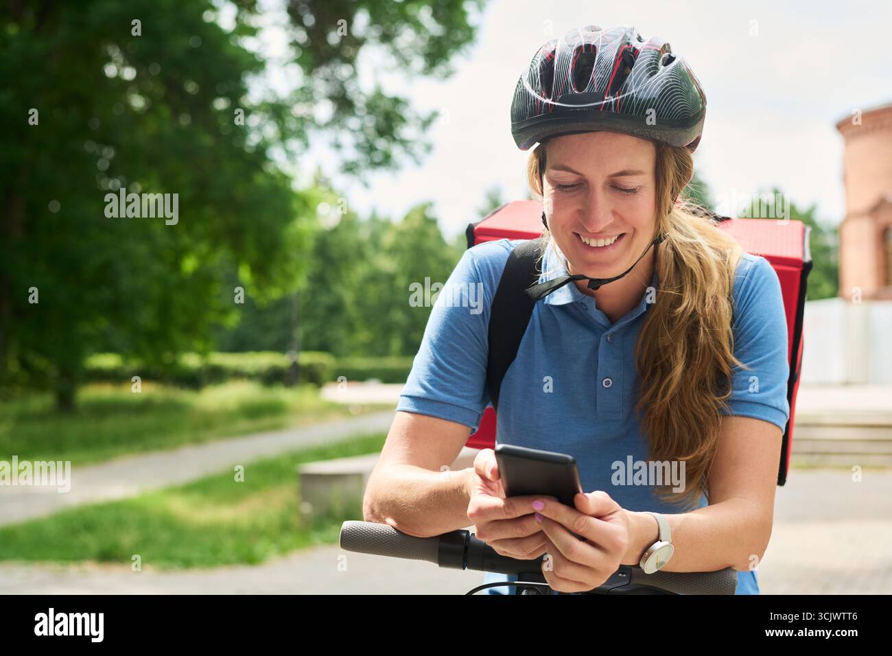 Woman Smiling While Using Smartphone Outdoors Stock Photo