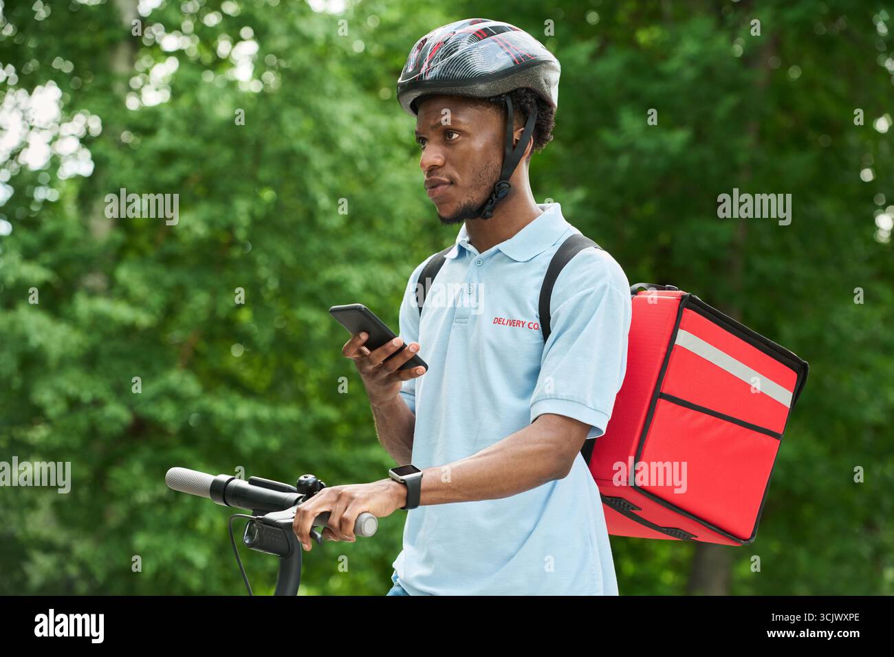Black Man Riding Bicycle Delivering Food Using Smartphone Stock Photo