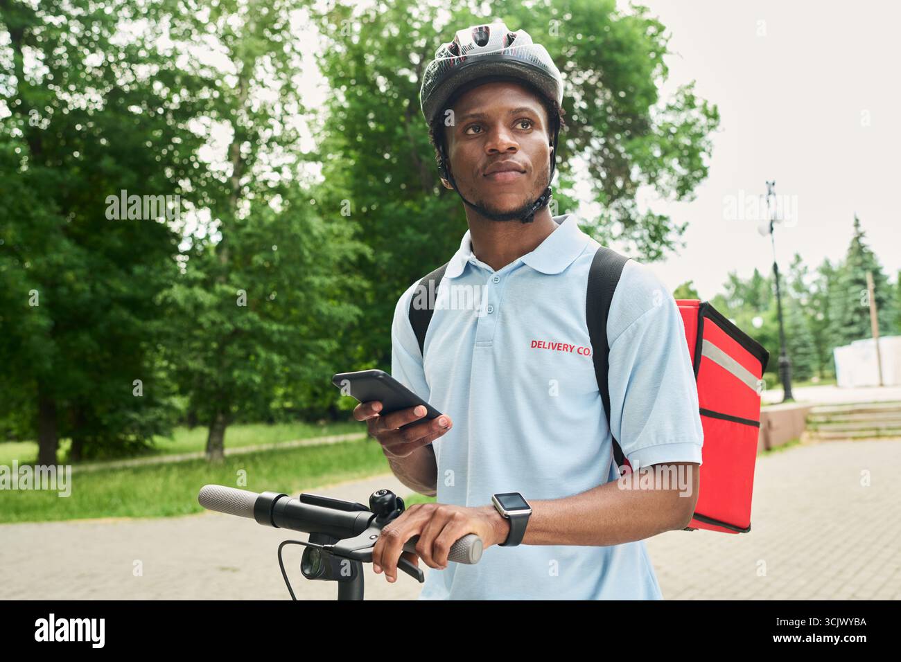 Black Man Using Smartphone While Delivering Food Outdoors Stock Photo