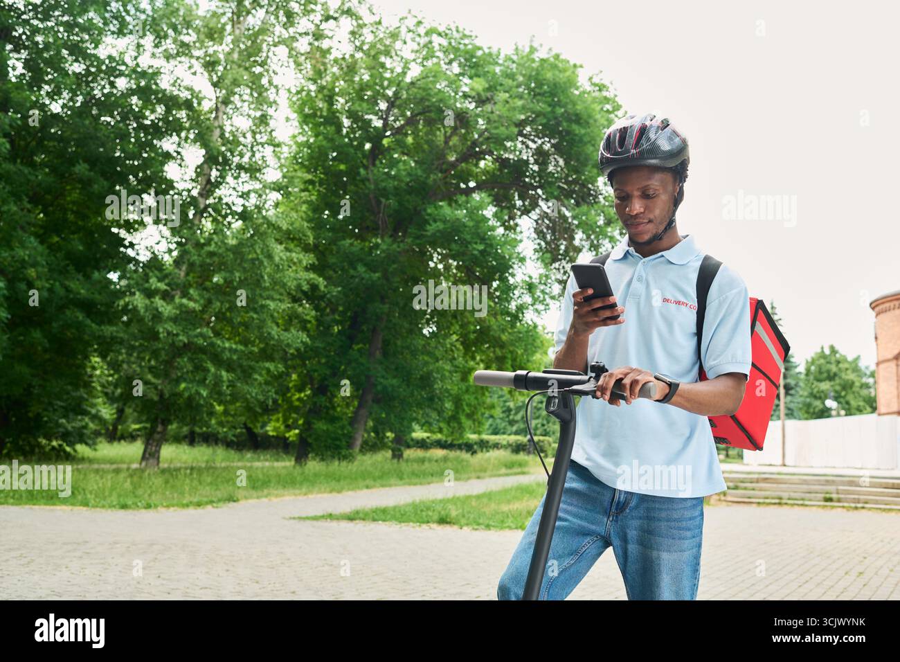 Black Man Using Smartphone While Standing with Electric Scooter Outdoors Stock Photo
