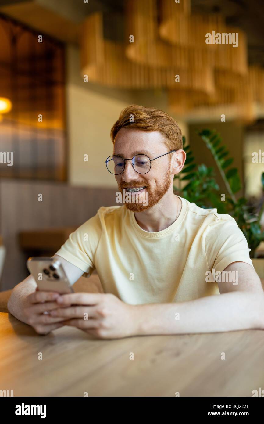 Redhead enjoying free time while using phone in cafe Stock Photo