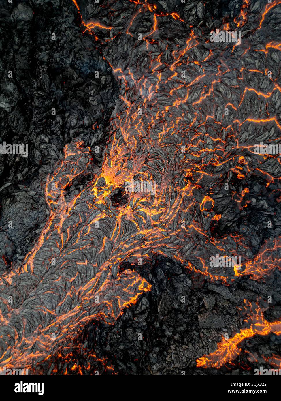 Aerial view of molten lava flowing through rugged, dark volcanic rock ...