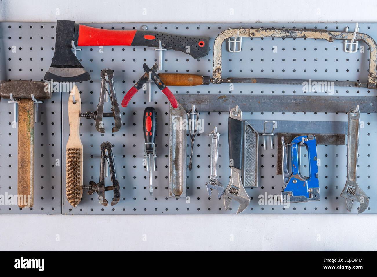 Work tools hanging on steel wall as background in workshop, close up Stock Photo
