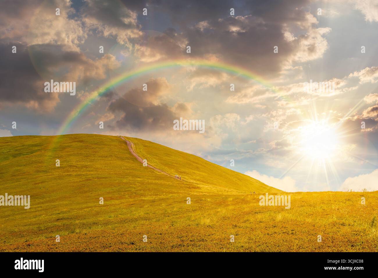 path for mountain tourism in summer at sunset. alpine landscape in evening light. beautiful scenery of ridge with green hills under rainbow and blue s Stock Photo