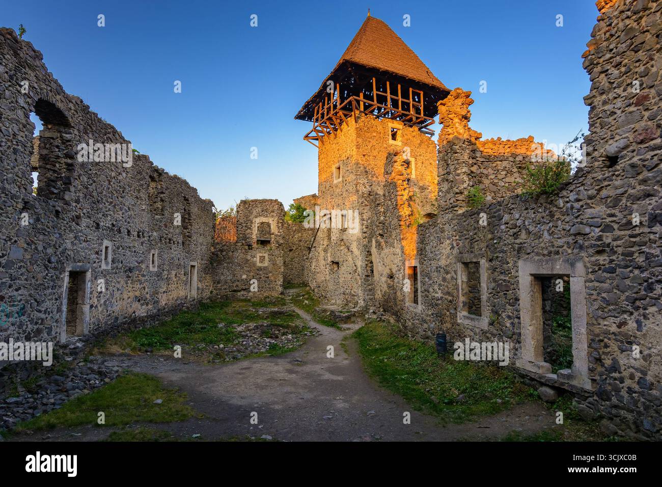 nevytske, ukraine - 19 may, 2018: castle with tower and stone wall at sunset. medieval fortress architecture of ukraine. travel destination and herita Stock Photo
