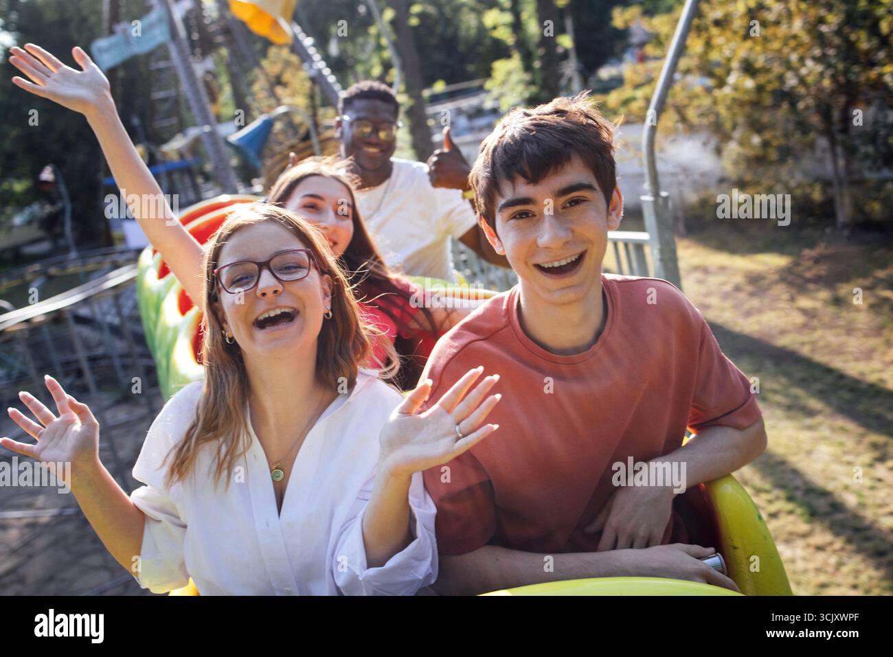 Young friends are having fun on a roller coaster ride at an amusement ...
