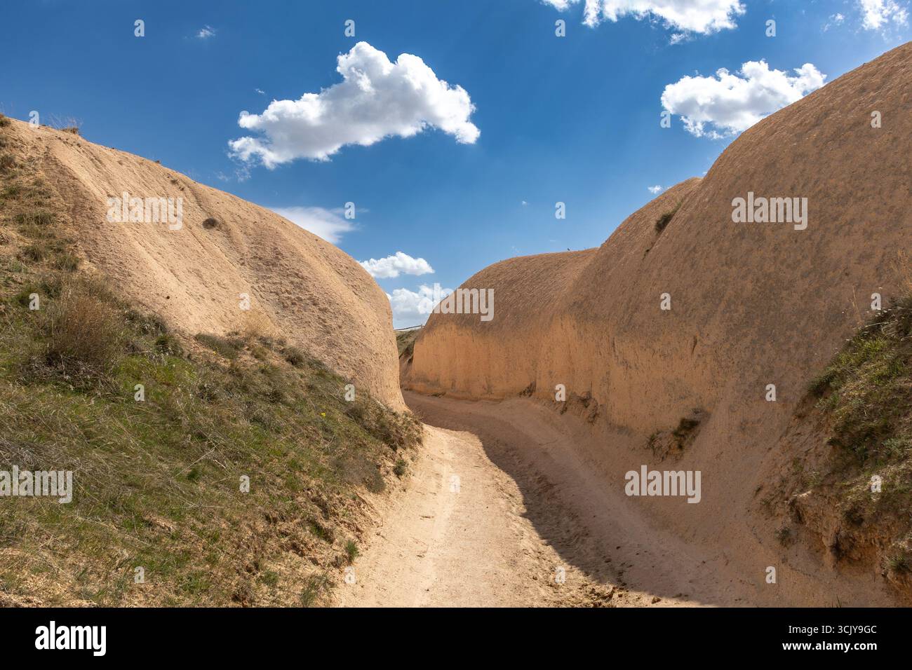 a soil path with a narrow cliff each side of it on a cloudy day Stock Photo