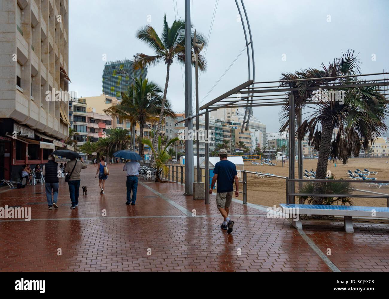 Las Palmas, Gran Canaria, Canary Islands, Spain. 9th September, 2025. A few British tourists brave the rain on the city beach in Las Palmas as a weather front brings unsettled weather to Gran Canaria. Credit: Alan Dawson/Alamy Live News Stock Photo