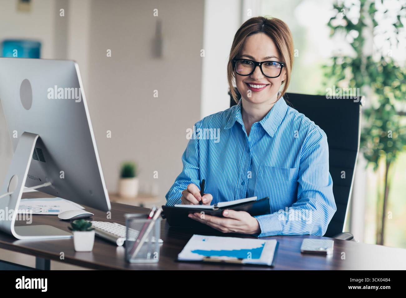 Professional female entrepreneur working at a desk in an office workspace with a focus on productivity and leadership Stock Photo