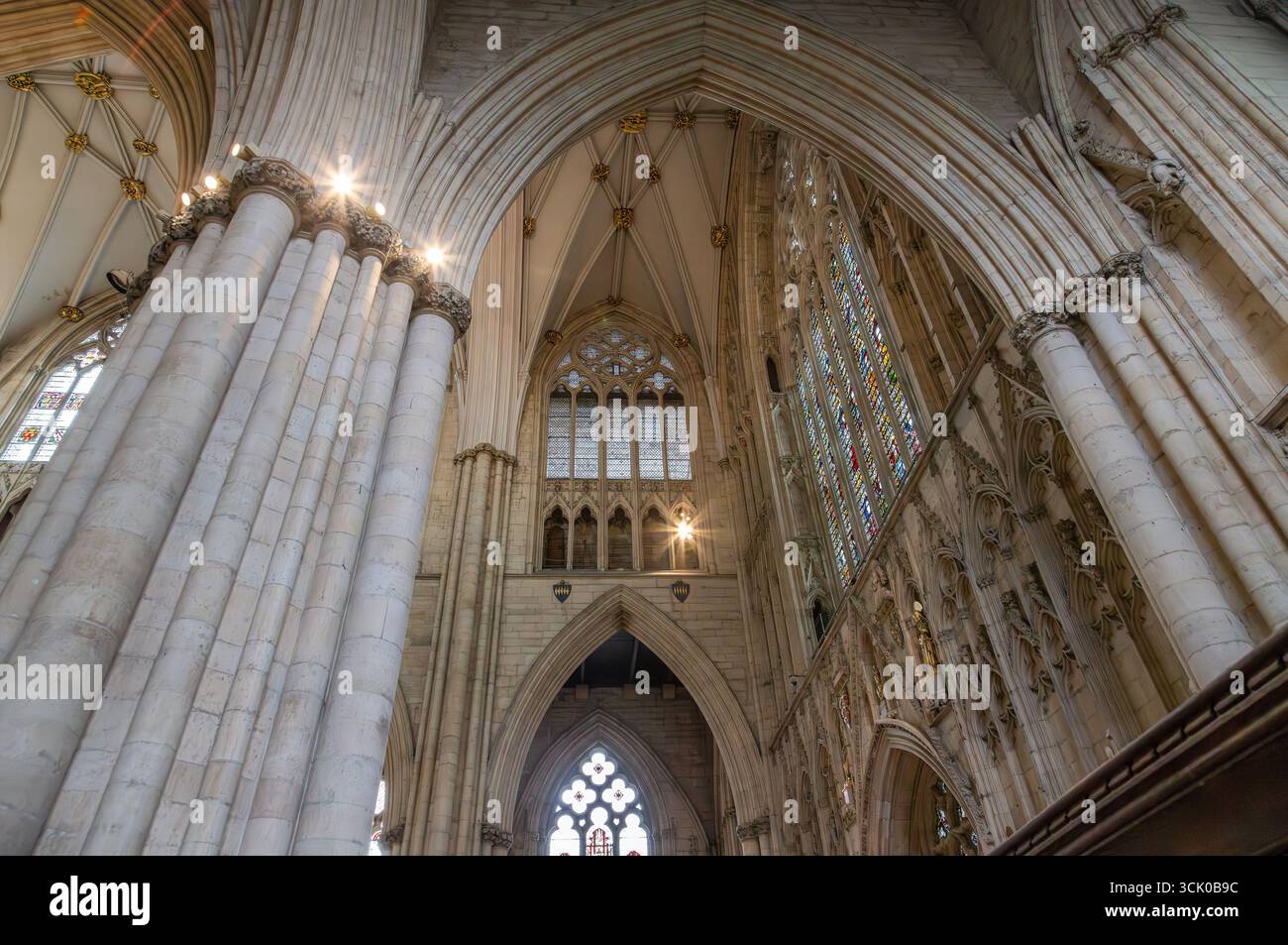 York Minster Cathedral interior in York, with Gothic architecture, stained glass windows, ribbed vaults, clustered columns, and ornate stone carvings Stock Photo