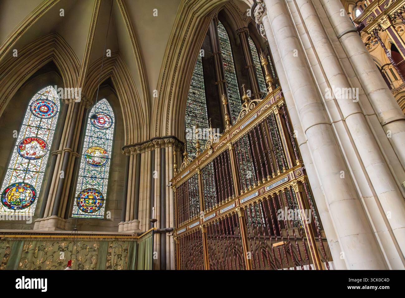 York Minster Cathedral interior with vibrant stained glass windows, pointed arches, and an ornate Gothic style choir screen in York, England. Stock Photo