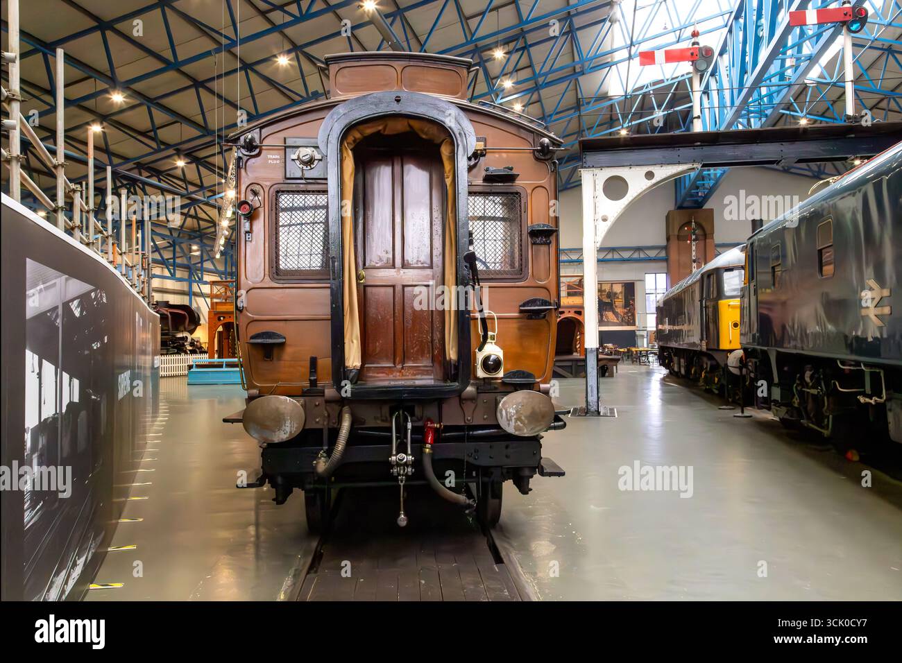 Historic railway carriage displayed inside the National Railway Museum in York, England, surrounded by other trains and museum interior architecture Stock Photo