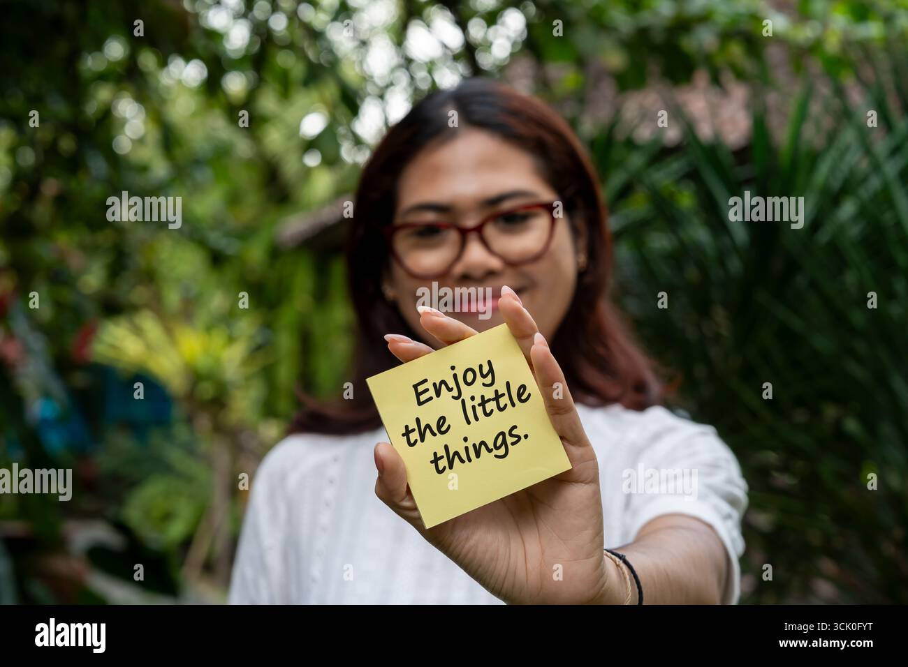 Women holding a note with inspirational quotes Enjoy the little things Stock Photo