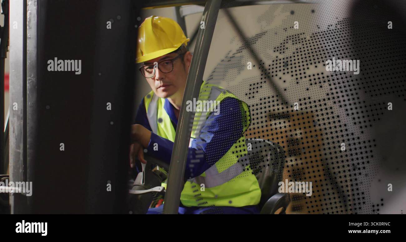 Operating Korean forklift operator steering controls in warehouse, wearing hard hat and safety vest Stock Photo