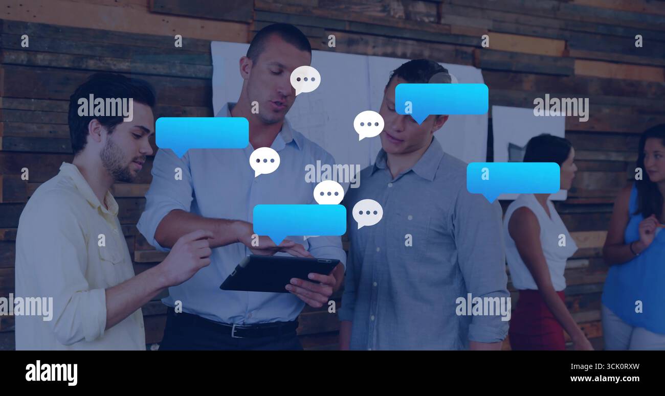 Collaborating colleagues discussing project on tablet in workspace, with digital speech bubbles Stock Photo