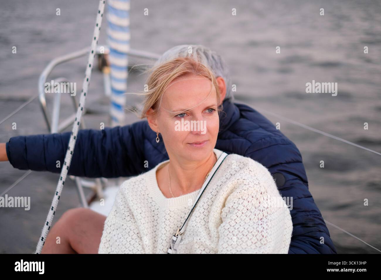 An elderly couple is sailing on a boat, surrounded by tranquil waters, showcasing their elegant style and enjoyment of life in a picturesque outdoor e Stock Photo
