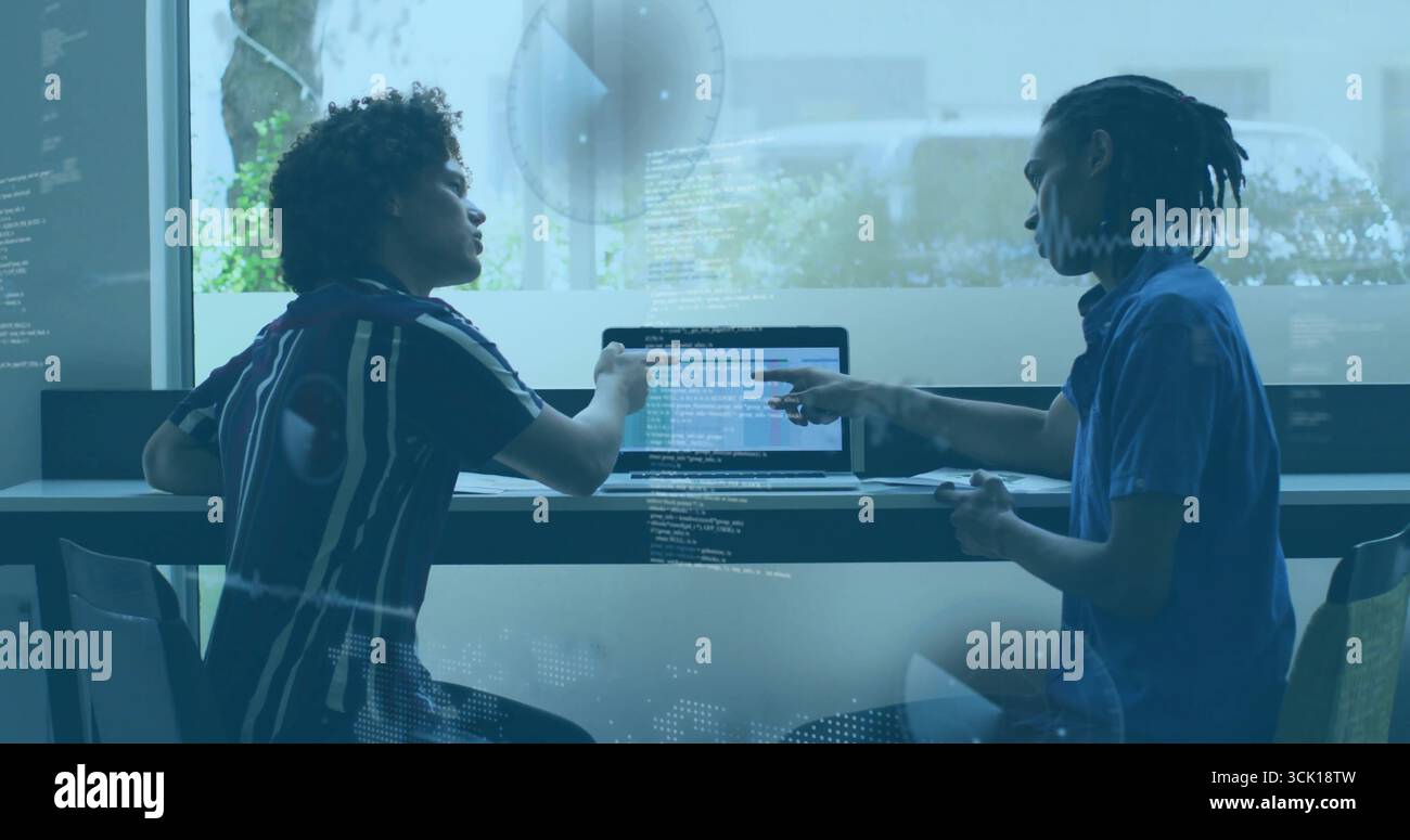 Developers collaborating on laptop typing code in meeting room, with glass reflections Stock Photo