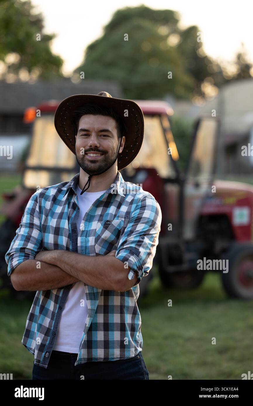 Handsome farmer standing with his arms crossed with confidence in front ...