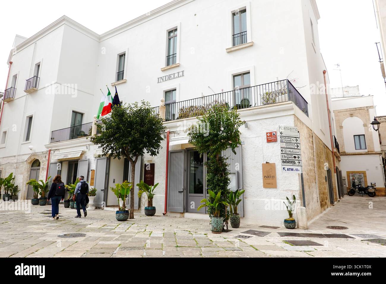 Couple walks past the Hotel Palazzo Indelli, located on the Piazza Garibaldi in the old port of Monopoli, Apulia, Italy. Stock Photo