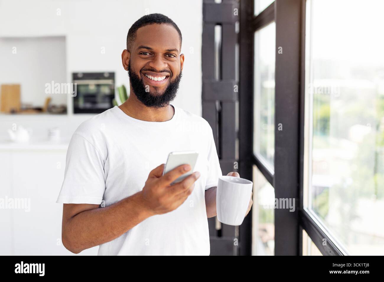 Black man using his smartphone drinking coffee Stock Photo