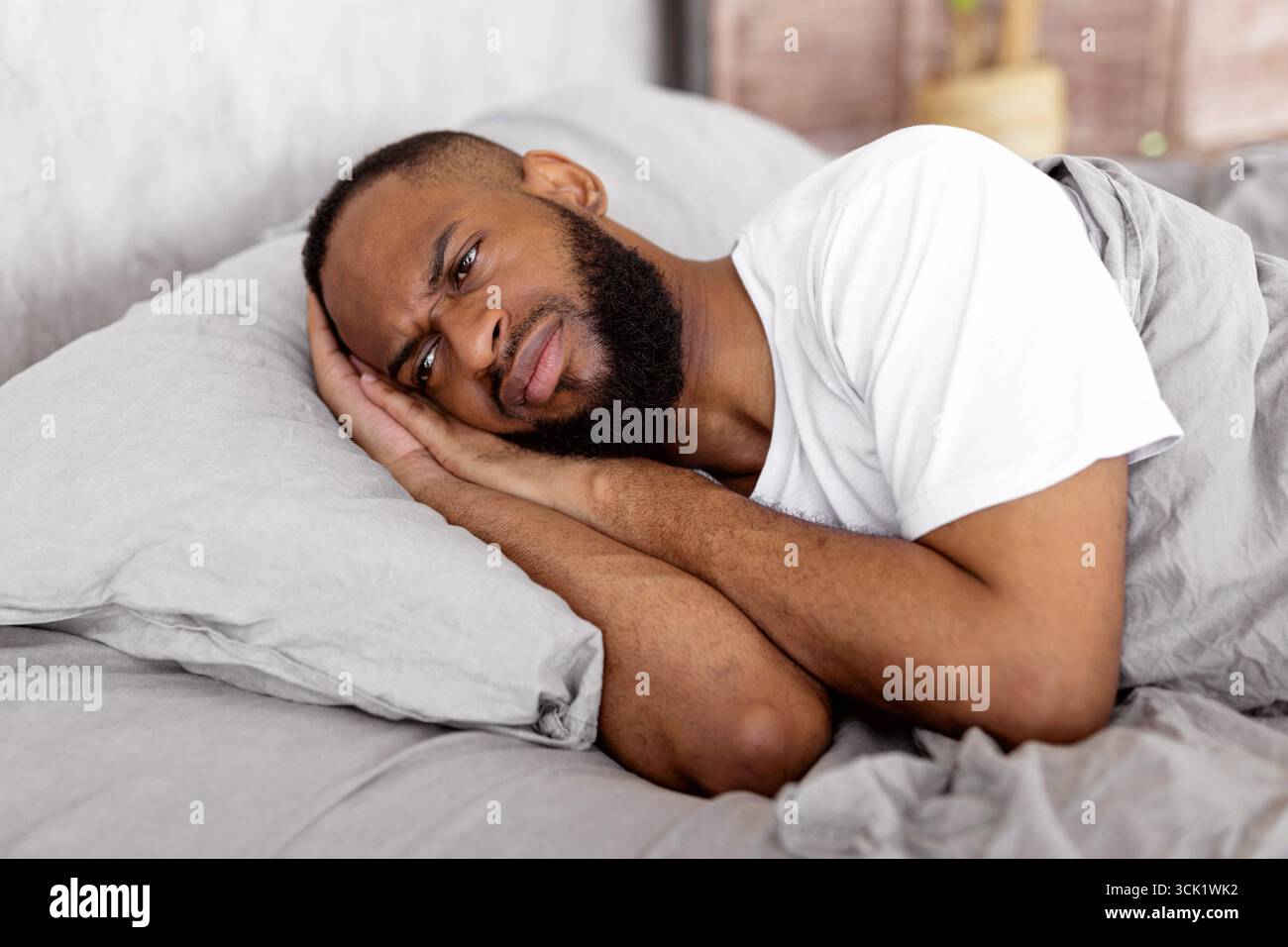 Black man lying in bed and thinking Stock Photo